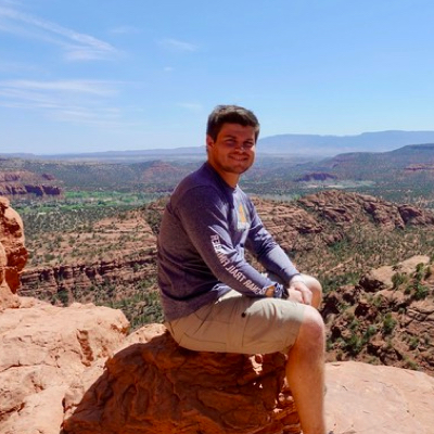 James sitting on a rock in front of a desert vista.