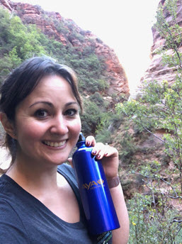 Aya travel nurse Leslie on a hillside smiling with her Aya water bottle.