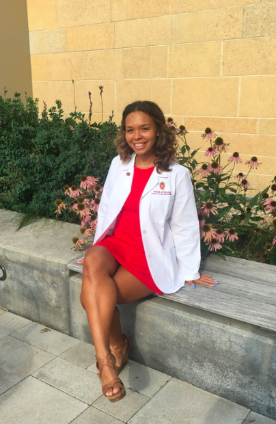 Nursing student smiles sitting on bench outside