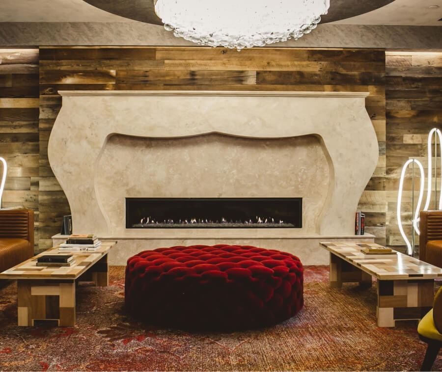 A lobby with a large red cushion in front of a fireplace